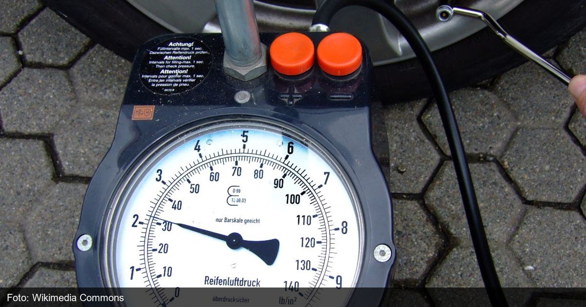 Motorista calibrando a pressão do pneu de um carro com calibrador manual